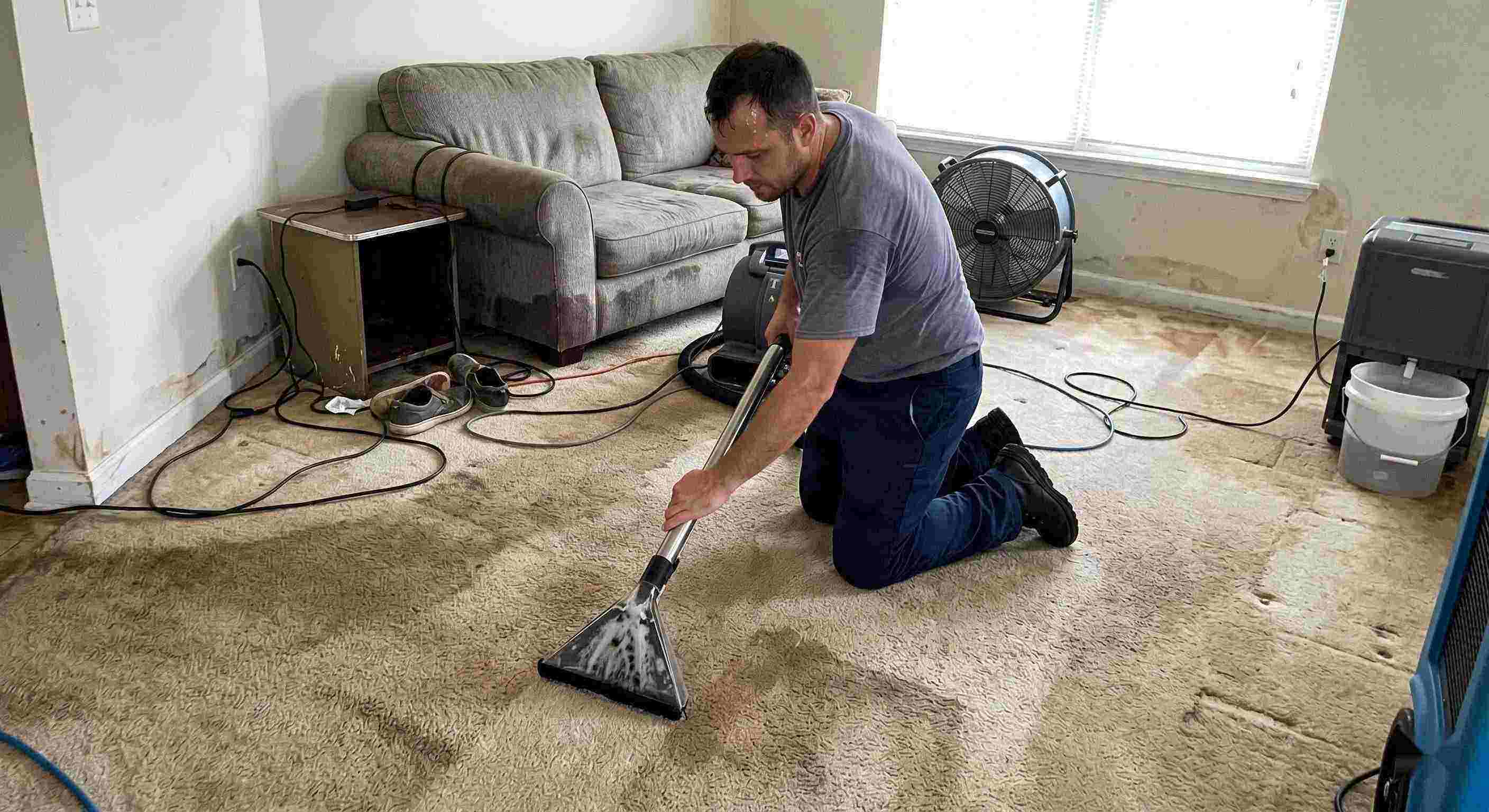 Technician performing carpet water extraction in a residential home using professional equipment after water damage in Cape Coral