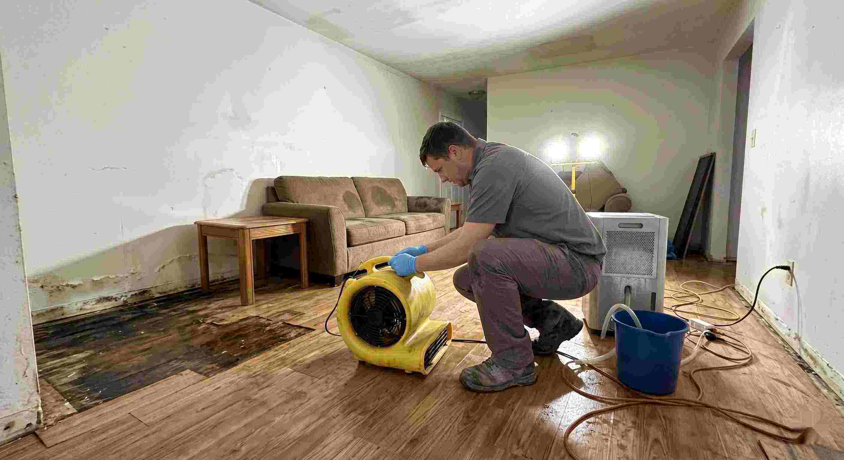 Trusted water damage restoration technician drying wet floors with equipment during cleanup process in Estero